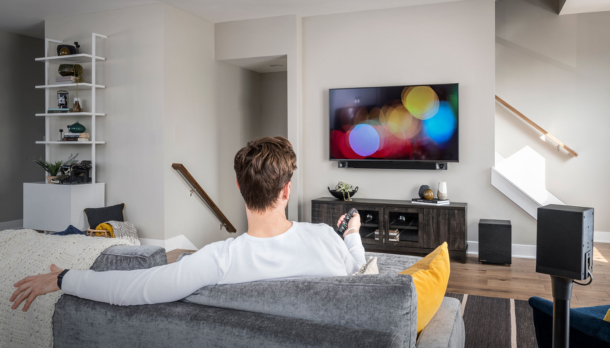 Muž se dívá na televizi v obývacím pokoji s Bar 48 5.1 Surround Sound System